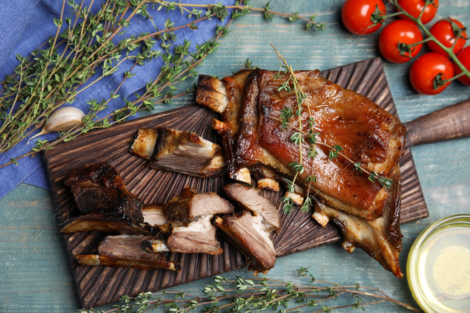 Photo of Delicious roasted ribs served on light blue wooden table, flat lay