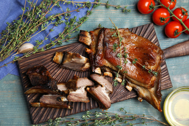 Photo of Delicious roasted ribs served on light blue wooden table, flat lay
