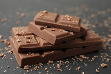 Photo of Pieces of tasty chocolate on grey table, closeup