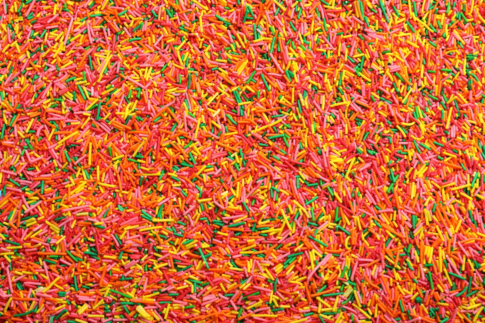 Photo of Bright colorful sprinkles as background, top view. Confectionery decor