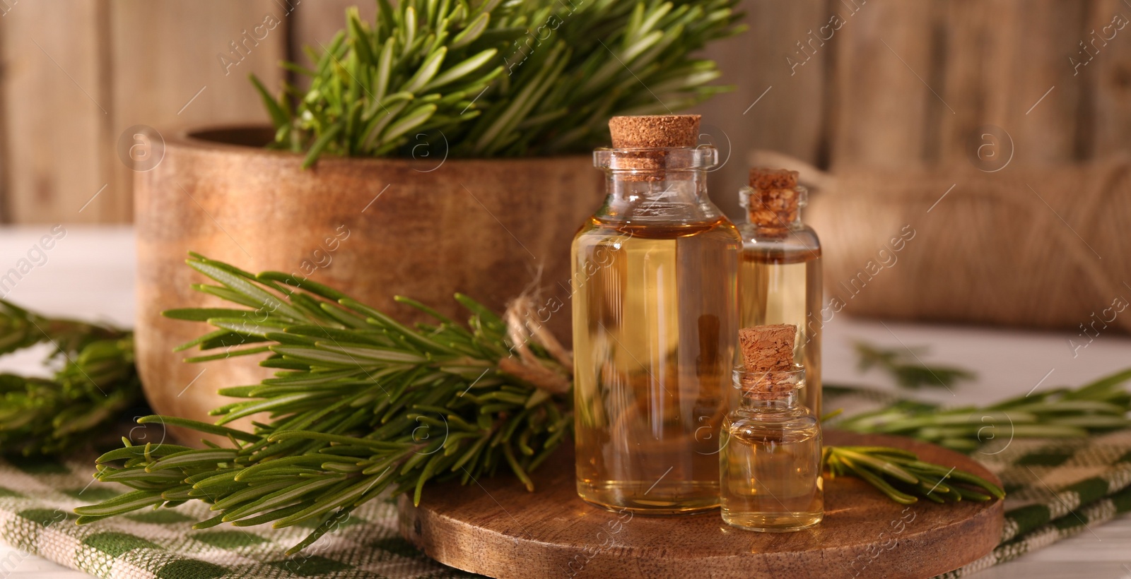 Photo of Essential oil in bottles and rosemary on table