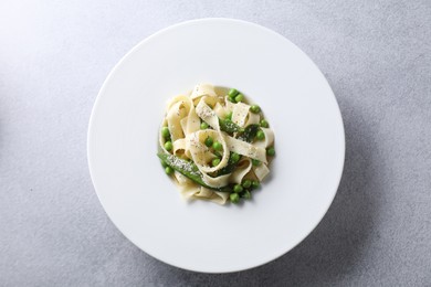 Photo of Delicious pasta with green peas on grey table, top view