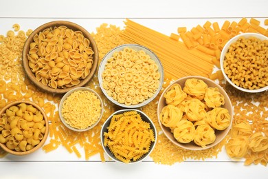Photo of Different types of pasta on white wooden table, flat lay