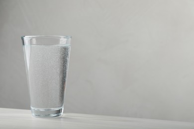 Photo of Glass of soda water on white wooden table. Space for text