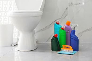 Photo of Toilet bowl and cleaning supplies in modern bathroom