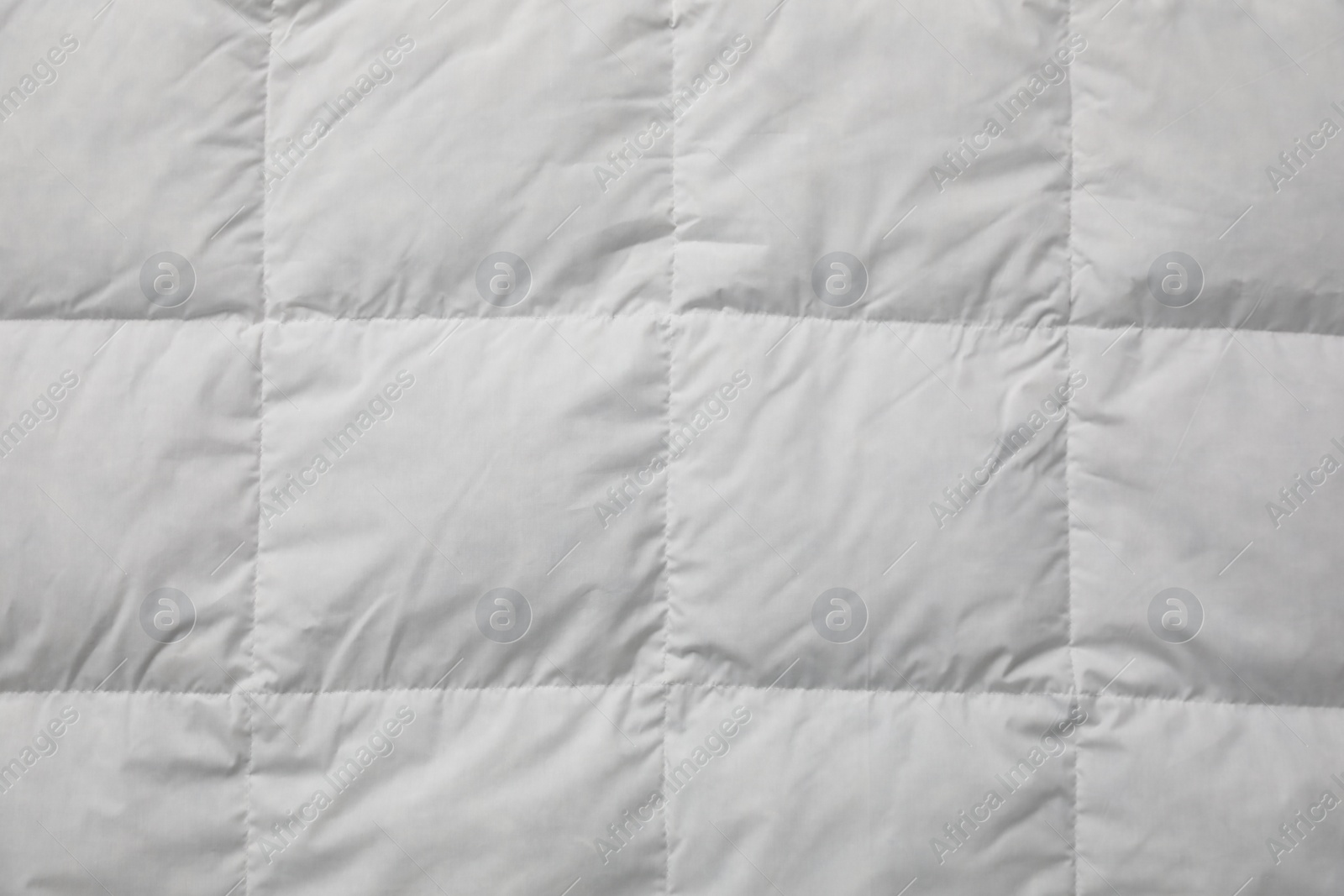 Photo of Soft quilted blanket as background, top view