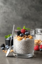 Photo of Delicious chia pudding with berries, granola and mint on grey table