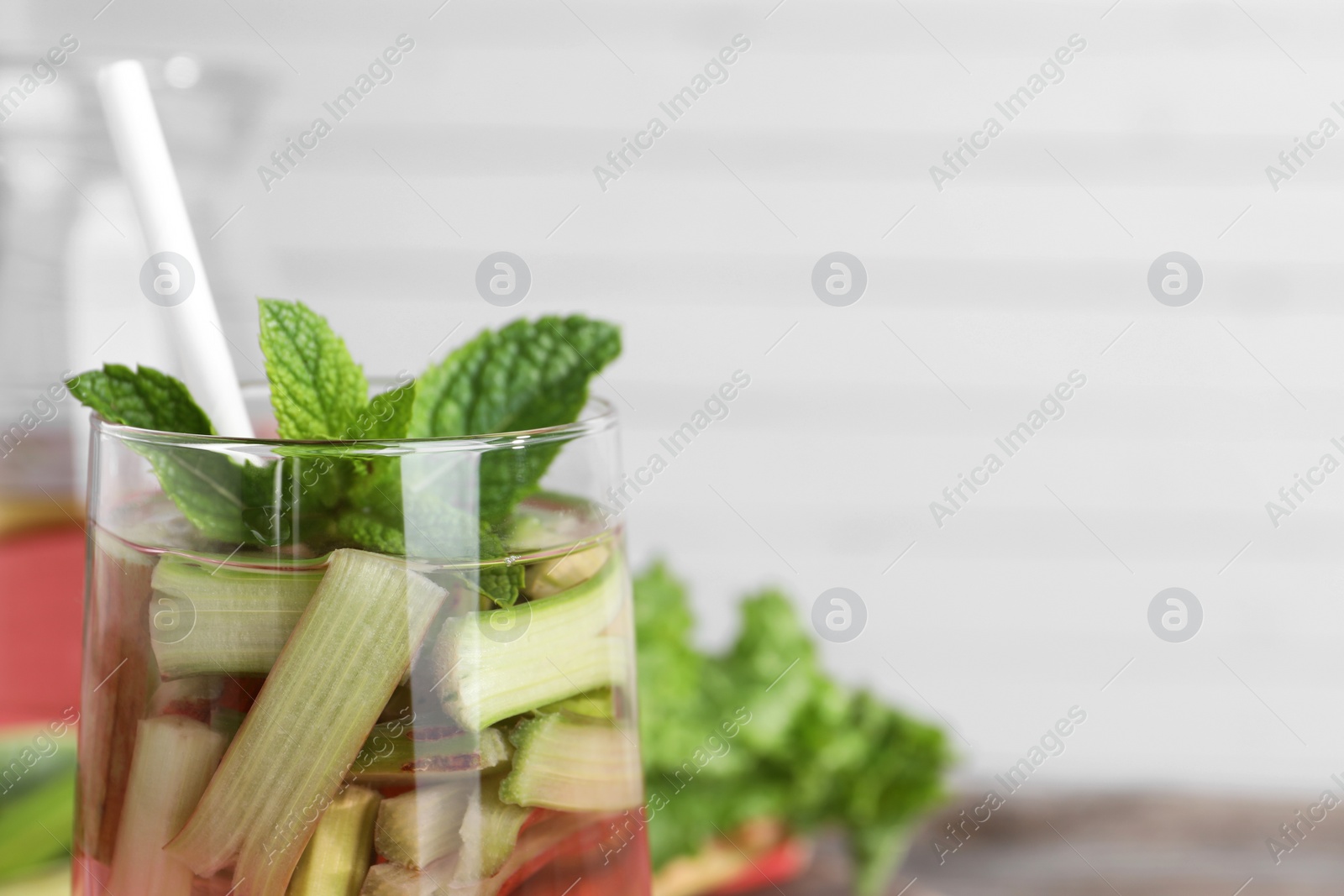 Photo of Glass of tasty rhubarb cocktail on blurred background, closeup. Space for text