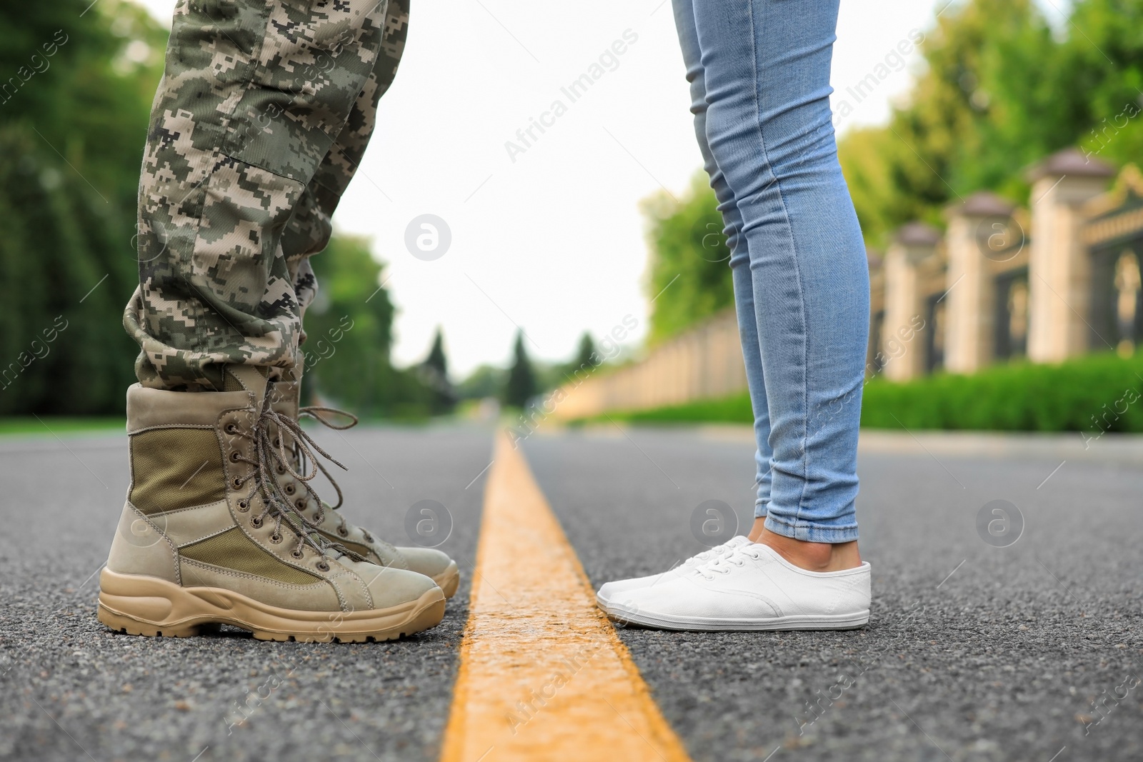 Photo of Man in military uniform and young woman separated by yellow line on road, closeup