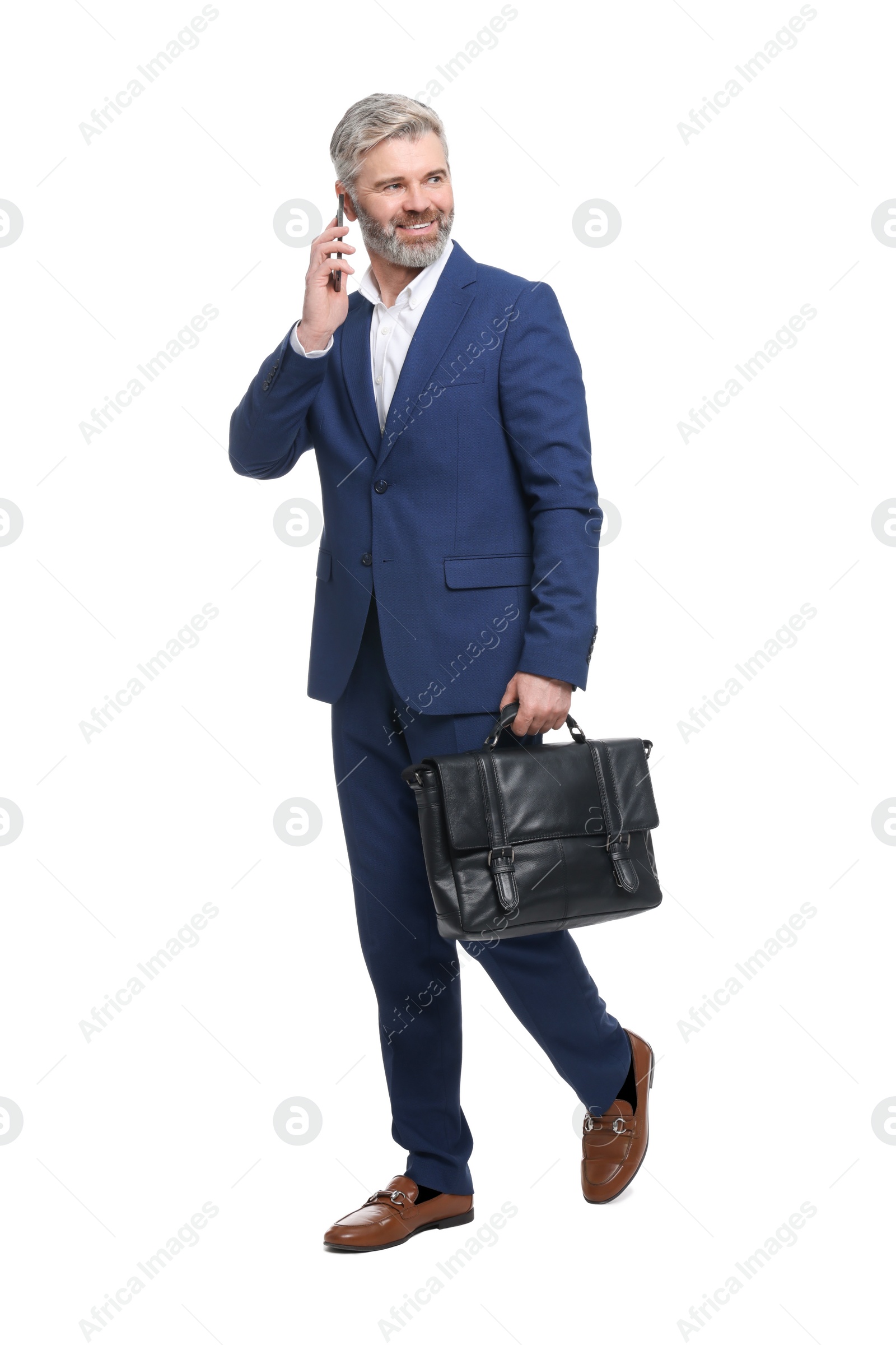 Photo of Mature businessman with briefcase talking on smartphone against white background