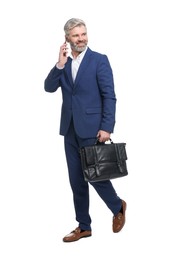 Mature businessman with briefcase talking on smartphone against white background
