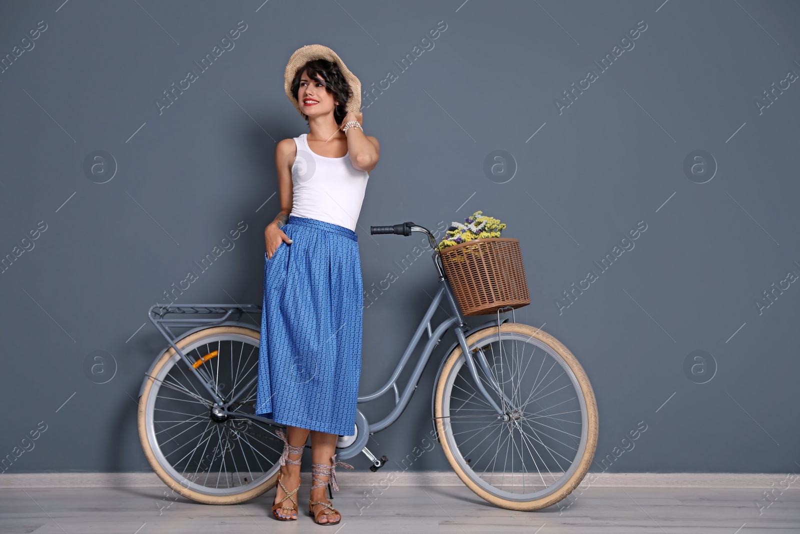 Photo of Portrait of beautiful young woman with bicycle near color wall