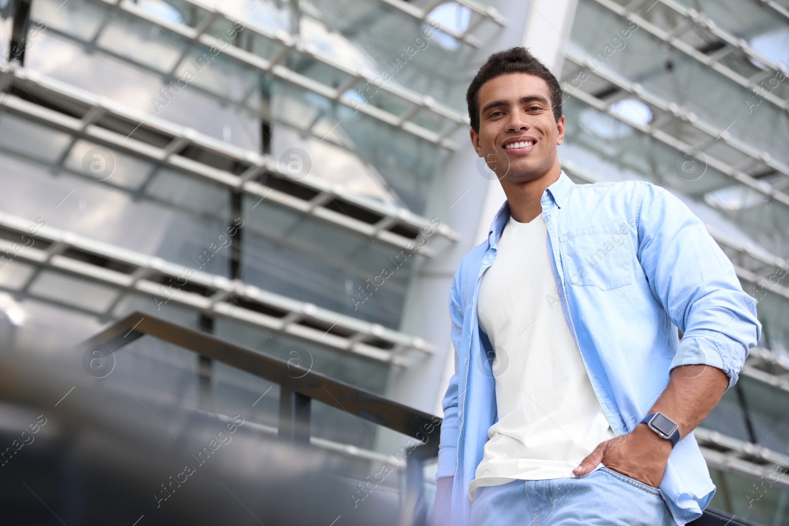 Photo of Handsome young African-American man on city street, low angle view. Space for text