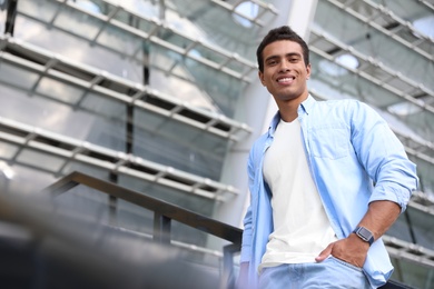 Handsome young African-American man on city street, low angle view. Space for text