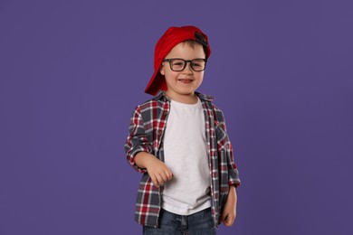 Photo of Cute little boy in glasses on purple background