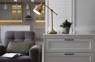 Stylish lamp on chest of drawers in room