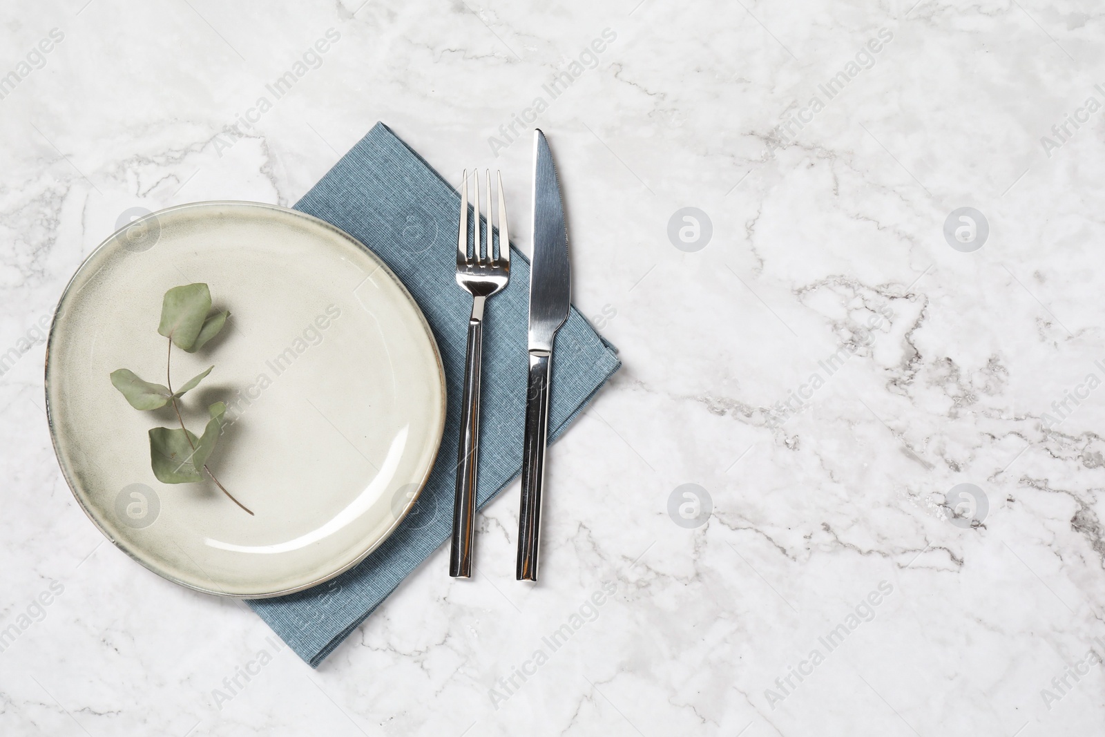 Photo of Stylish setting with elegant cutlery on white marble table, top view. Space for text