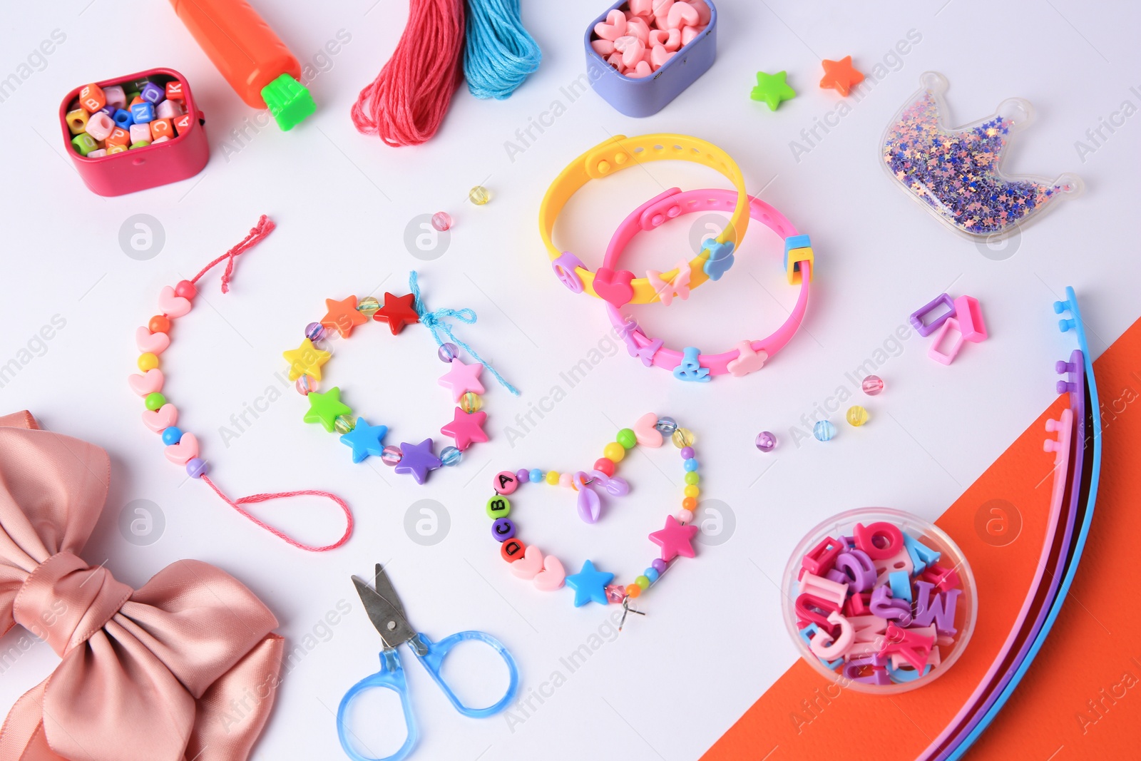 Photo of Kid's handmade beaded jewelry and different supplies on color background, above view