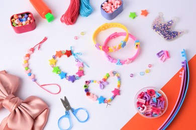 Photo of Kid's handmade beaded jewelry and different supplies on color background, above view