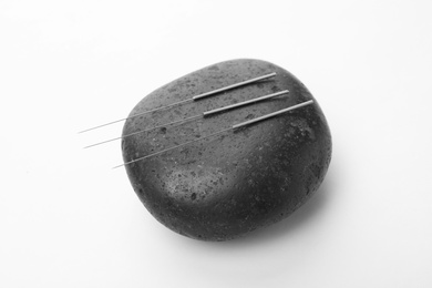 Photo of Acupuncture needles and stone on white background