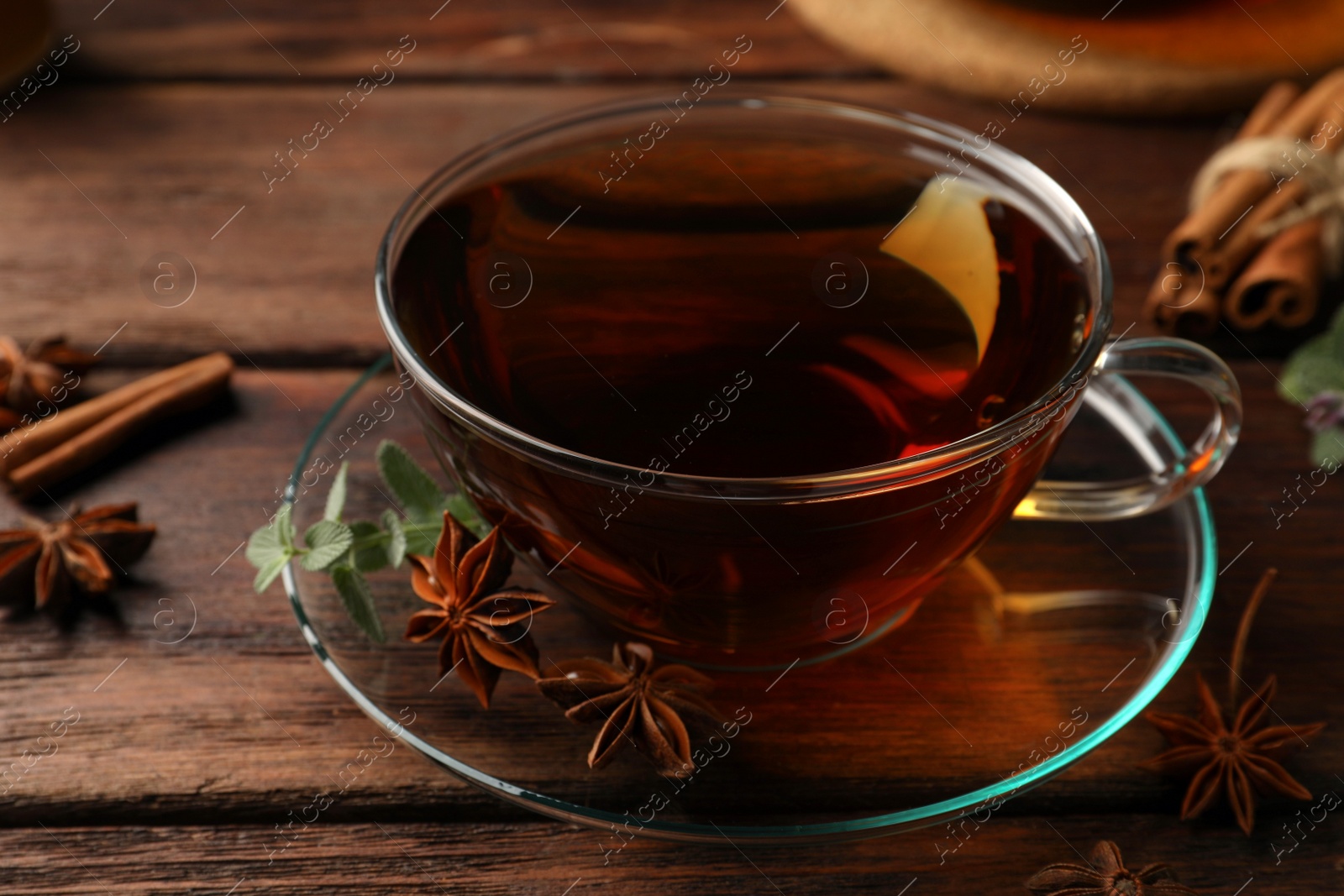 Photo of Aromatic tea with anise stars and mint on wooden table, closeup