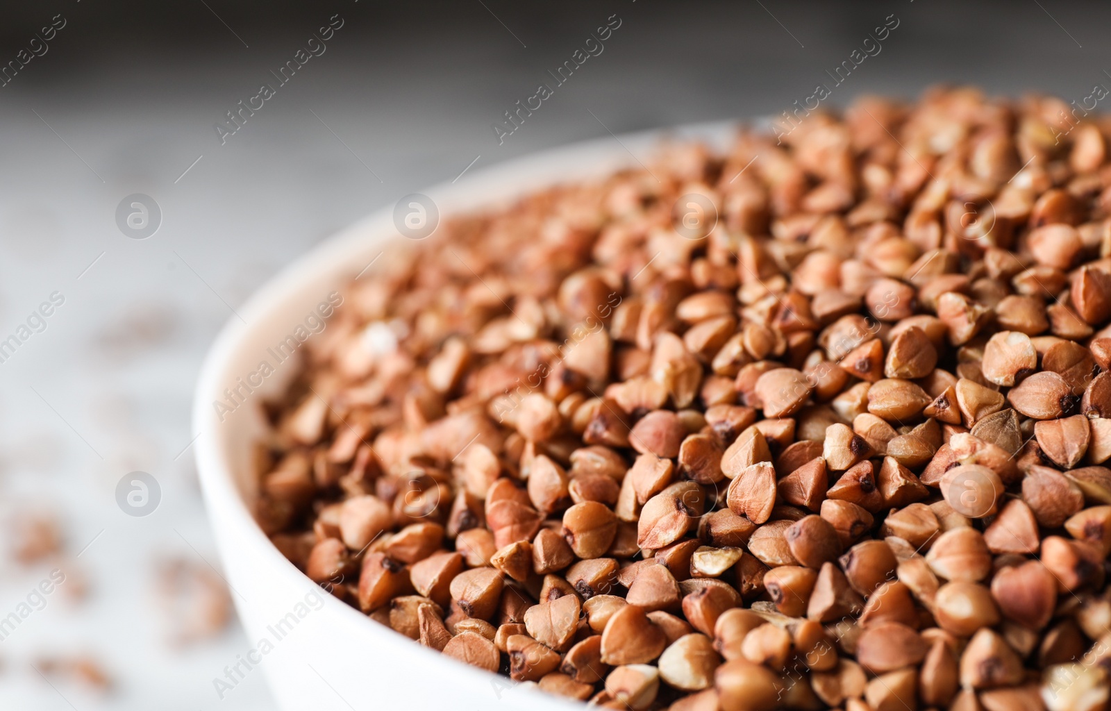 Photo of Uncooked organic buckwheat grains in bowl, closeup