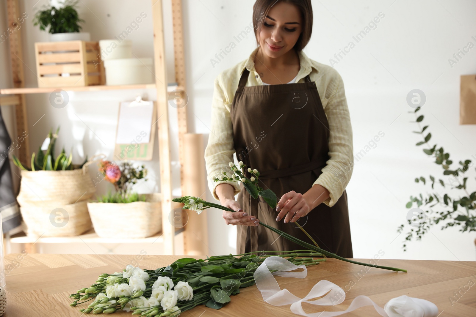 Photo of Florist making beautiful bouquet at table in workshop