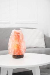 Photo of Himalayan salt lamp on white table in room