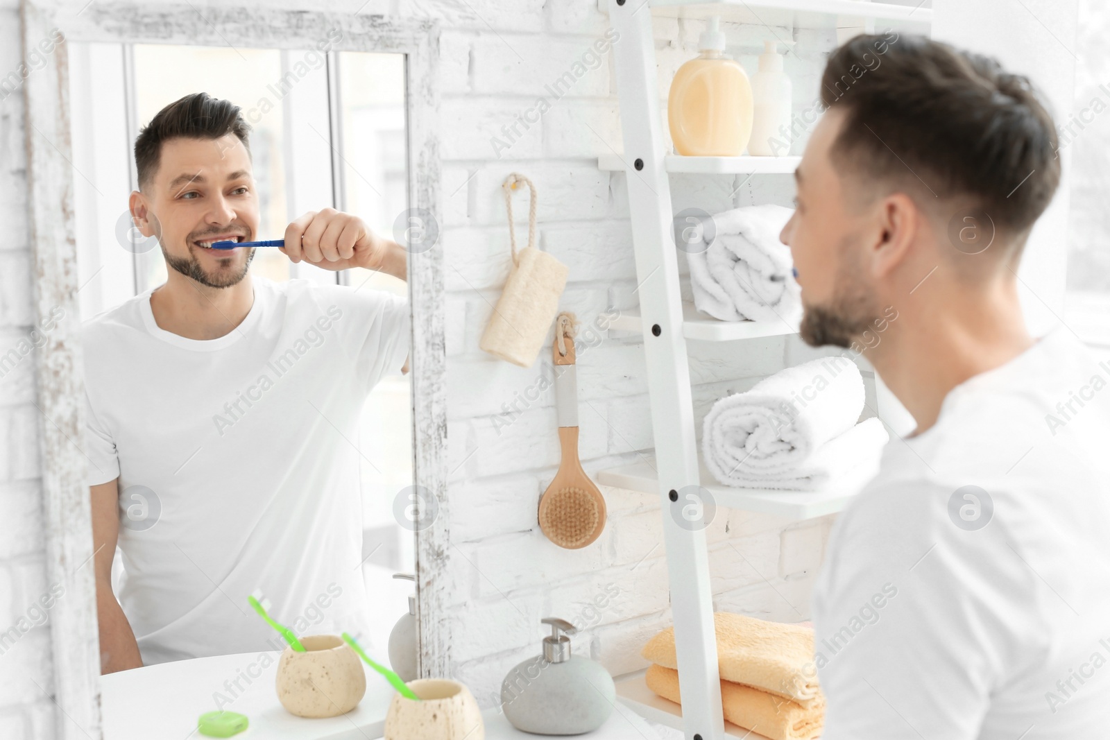 Photo of Young man brushing his teeth in bathroom