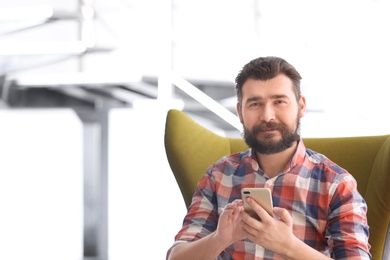 Photo of Portrait of confident mature man with mobile phone in armchair