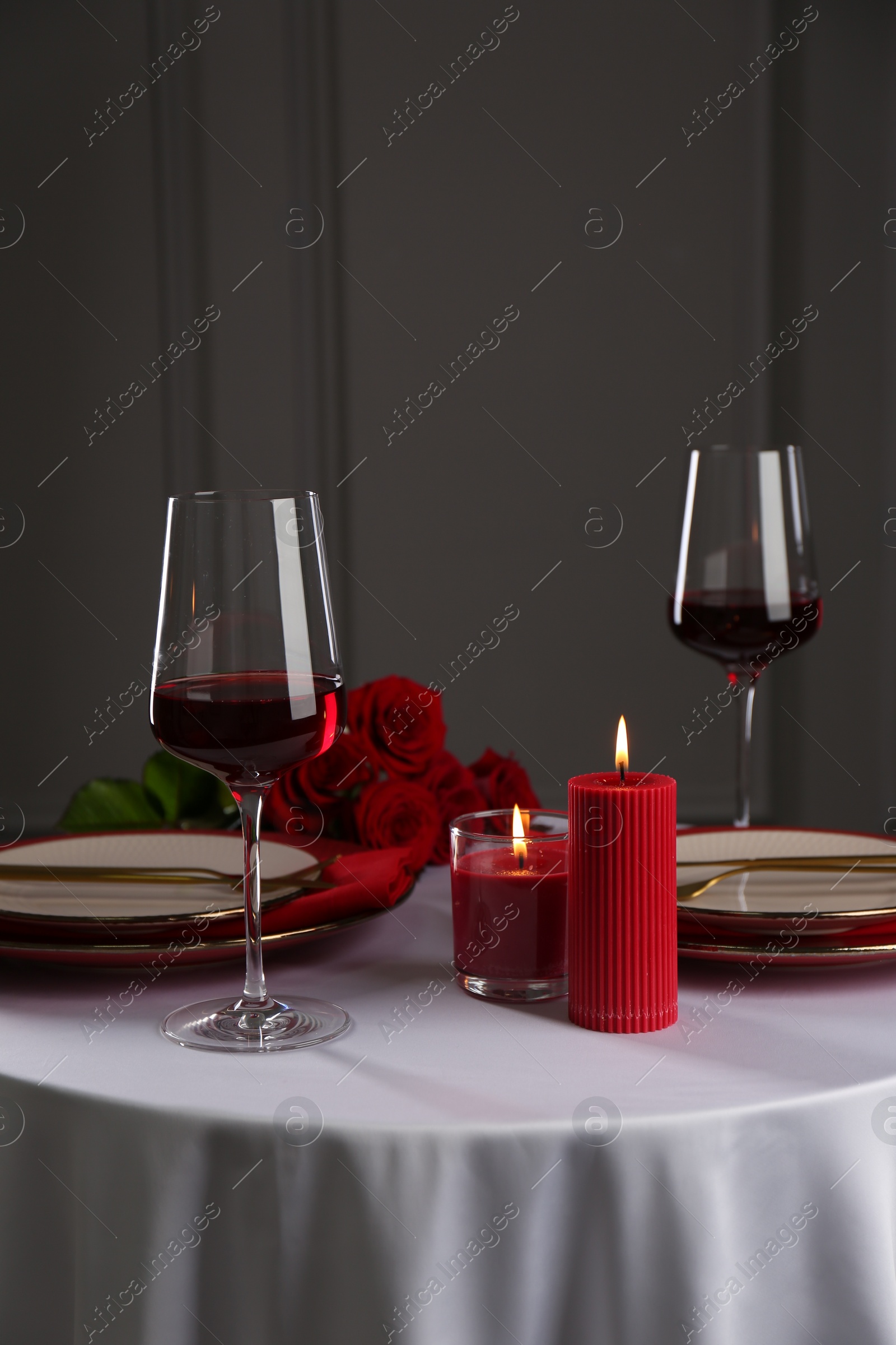 Photo of Place setting with candles and roses on white table. Romantic dinner