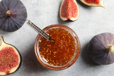 Photo of Glass jar with tasty sweet jam and fresh figs on light grey table, flat lay