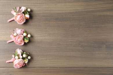 Beautiful boutonnieres on wooden background, flat lay. Space for text