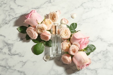 Photo of Beautiful composition with bottle of perfume and roses on marble background, top view