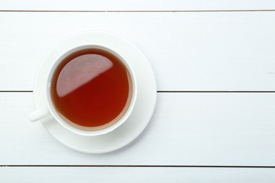 Photo of Aromatic tea in cup on white wooden table, top view. Space for text