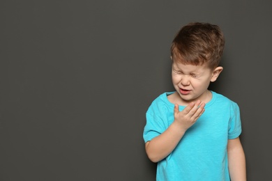 Photo of Cute boy suffering from cough on dark background. Space for text