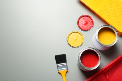 Flat lay composition with paint cans and brush on grey background. Space for text