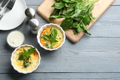 Photo of Tasty broccoli casserole in ramekins on wooden table, flat lay. Space for text