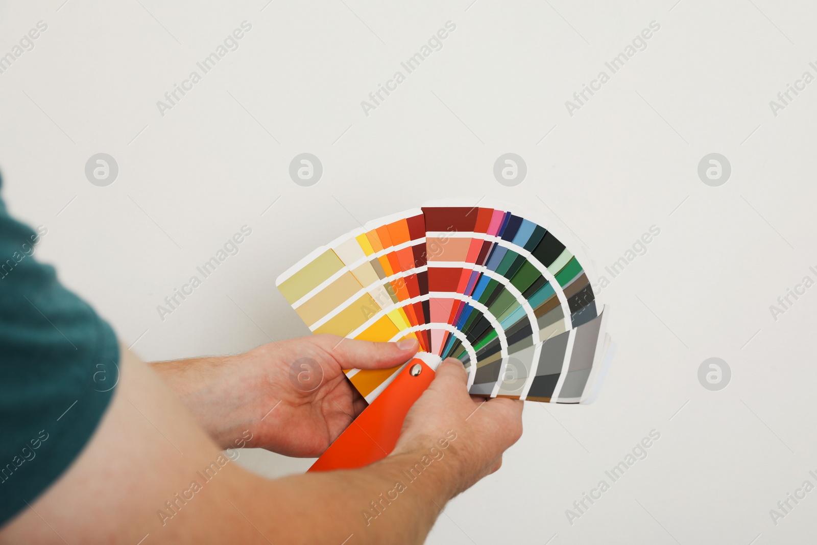 Photo of Man with palette choosing color for painting wall indoors, closeup. Interior design