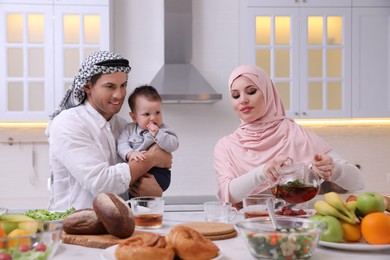 Happy Muslim family with little son at served table in kitchen