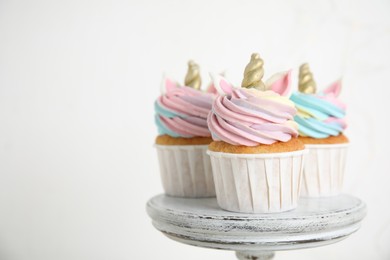 Cute sweet unicorn cupcakes on dessert stand against   white background. Space for text