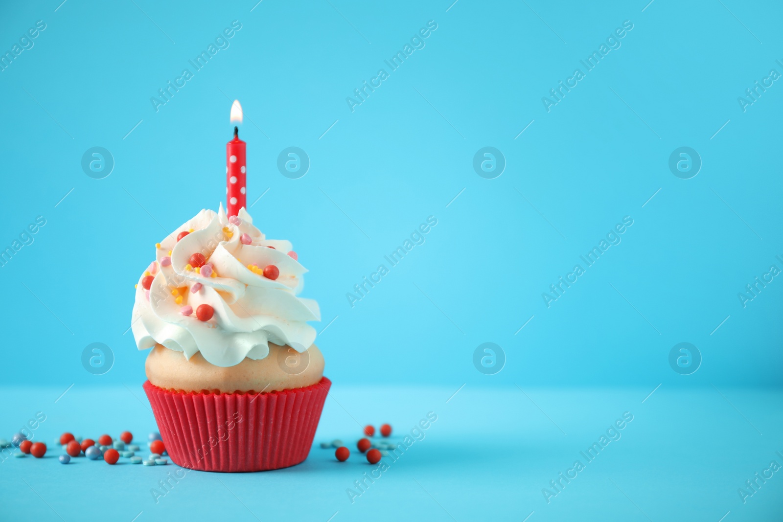 Photo of Delicious birthday cupcake with candle on light blue background. Space for text