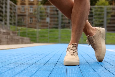 Man wearing stylish sneakers outdoors, closeup. Space for text