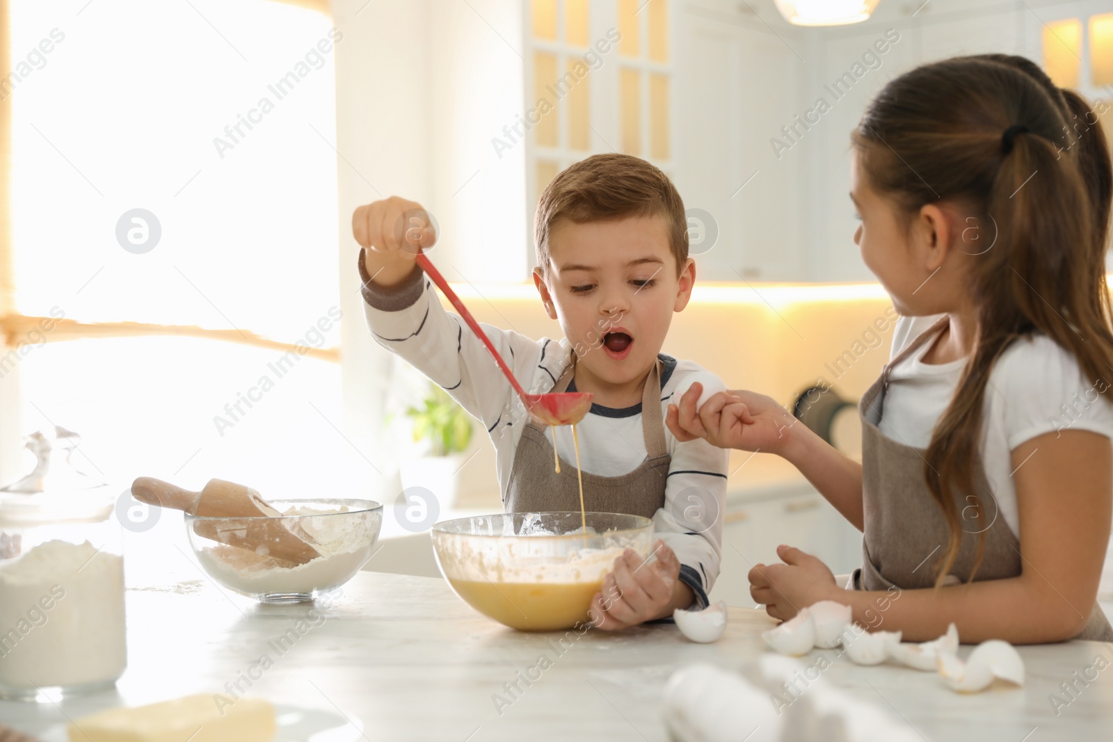 Photo of Cute little children cooking dough together in kitchen