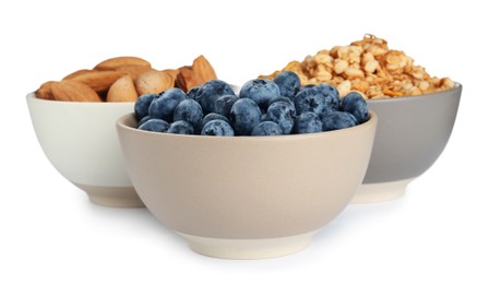 Photo of Ceramic bowls with almonds, blueberries and granola on white background. Cooking utensil