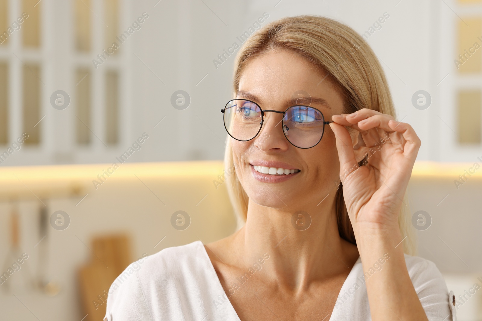 Photo of Portrait of smiling woman with stylish glasses in kitchen. Space for text