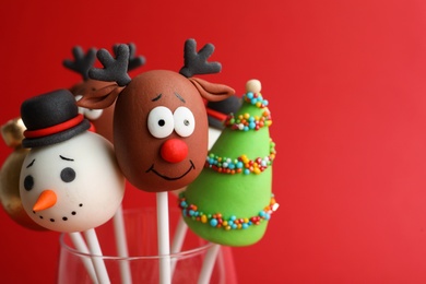 Photo of Delicious Christmas themed cake pops on red background, closeup