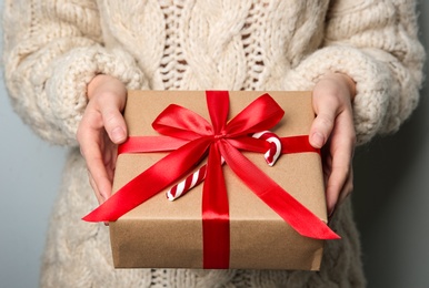 Photo of Woman holding Christmas gift box on grey background, closeup