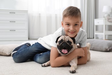 Boy with his cute pug on floor at home