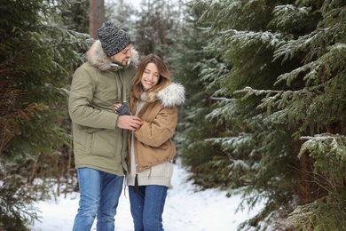 Photo of Couple in conifer forest on snowy day, space for text. Winter vacation